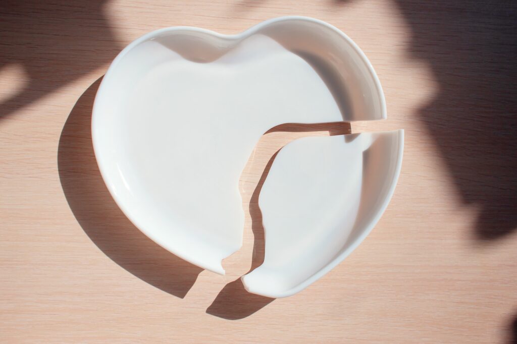 Broken heart-shaped plate. Cracked heart. Shards of broken dishes. Negligence